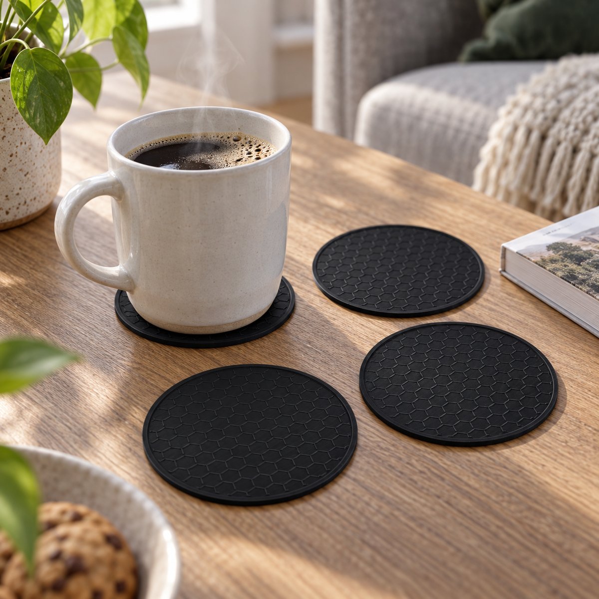 Fire svarte bordskånere med bikubemønster, én under en kaffekopp – illustrasjon av 3D-printet produkt i bruk