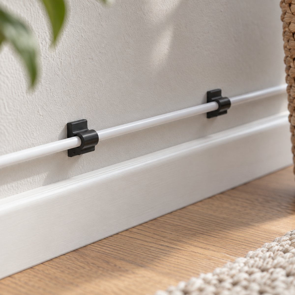 To kabelfester som holder en ledning langs gulvlisten – illustrasjon av 3D-printet produkt i bruk